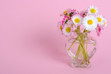 Pink background for valentines day card, vase with flowers in shape of heart.