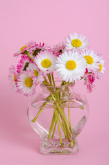 Pink background for valentines day card, vase with flowers in shape of heart.