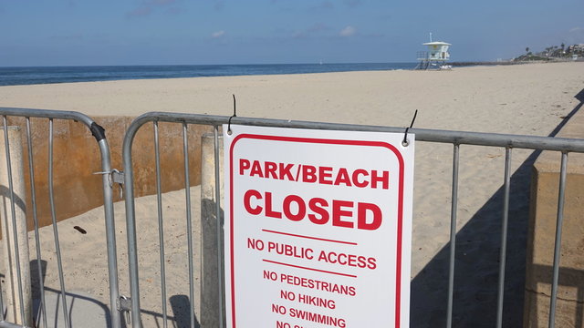 Sign and fences restrict access to all public beaches in Carlsbad, CA due to Covid-19 precautions.