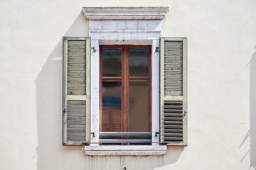 Obraz premium Italian window on the bright wall facade with open wooden shabby bright-green color shutters