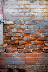 Deteriorated and worn old red brick wall with grey blue paint on some bricks and rusted drain pipe
