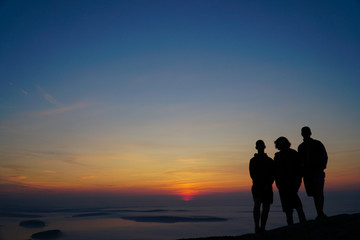 silhouette of family on mountain in sunrise