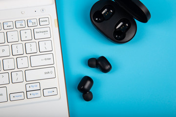 White Keyboard with Wireless bluetooth headphones isolated on blue background