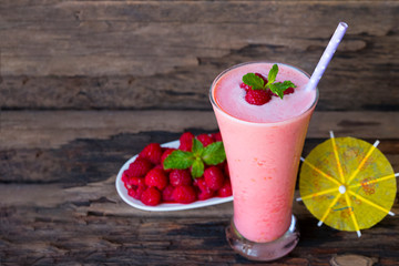 Raspberry smoothie red colorful fruit juice milkshake blend beverage healthy high protein the taste yummy In glass drink episode morning on a wooden background.