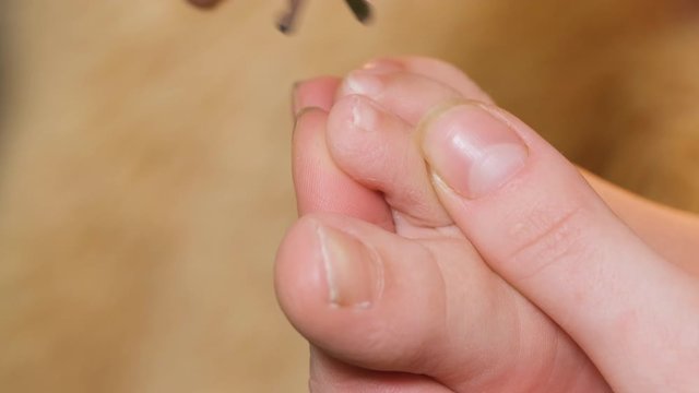 Close Up Fingers Of Woman Holding Baby Leg. Mom Cuts Her Son's Nails On Two Toes After Bathing. Childcare.