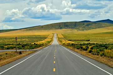 Two lane road heading to low hills in Eastern Oregon desert