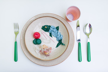 Plastic pollution comes to our tables. Plastic and microplastics pollute the sea and We eat fish wit that have absorbed plastic. Dish with fish and side dishes made of plastic. Isolated on white.