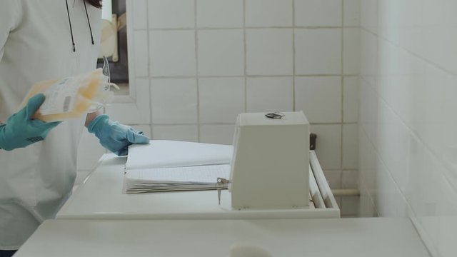 Laboratory worker seals bag with donated plasma. Blood Donation Center. Nurse doing notes on pack with donor