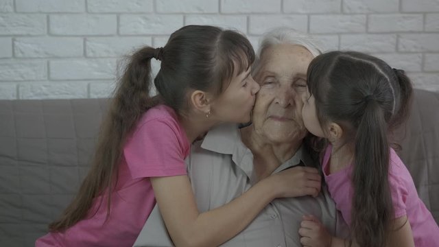 Children kiss grandmother. Little sisters kiss their old granny. Kiss Granny.