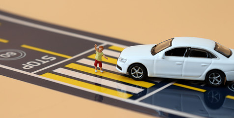 A miniature boy who raises his hand and crosses the crosswalk a miniature car that crossed the stop...