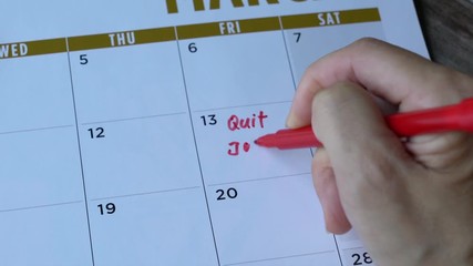 Woman writing quit job words with red marker pen on a calendar. Unemployment or frustration with job concept. 