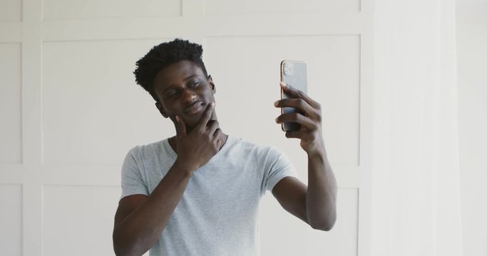 Handsome african man making selfie, admiring himself in cellphone