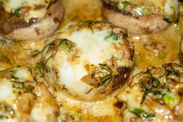 Mushrooms baked in the oven with cheese, green onions and dill. Close up.