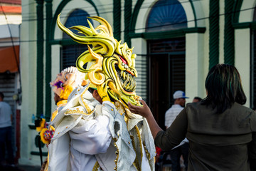 native men in shiny varicolored costumes pass by city street at dominican carnival