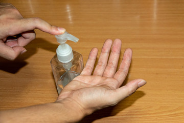 Closeup shot of a man is cleaning his hands with alcohol gel in house to prevent COVID-19 or Corona Virus infection. People use alcohol gel for sanitation during the 2019-nCoV outbreak. 