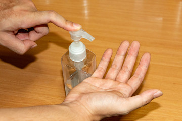 Closeup shot of a man is cleaning his hands with alcohol gel in house to prevent COVID-19 or Corona Virus infection. People use alcohol gel for sanitation during the 2019-nCoV outbreak. 