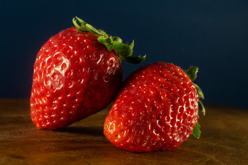 Closeup of two fresh and ripe strawberries on a wooden surface