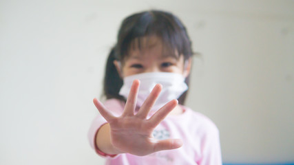 Little girl wearing mask for protect pm2.5 and show stop hands gesture for stop corona virus outbreak, focus hand.
