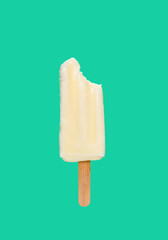 milk shake popsicle with a bite on a green background