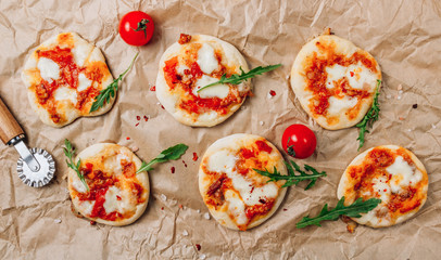 Pizzete. Home baked mini pizzas bolognese. Tomato sauce ,mozzarella cheese and minced meat. Rustic paper table. Stay at home concept