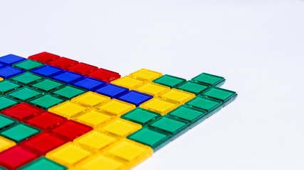 Colorful matching blocks like tetris on white background, high contrast colours, red blue yellow and green transparent tiles matched to create a mosaic pattern, game for kids, copy space