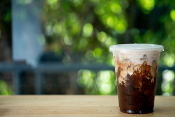 Ice coffee on a wood table with cream being poured into it showing the texture