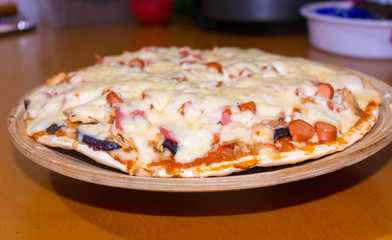 Freshly baked traditional Italian Pizza with tomato sauce, cheese and sausage on wooden table background, front view. Grandmother's recipe. Homemade