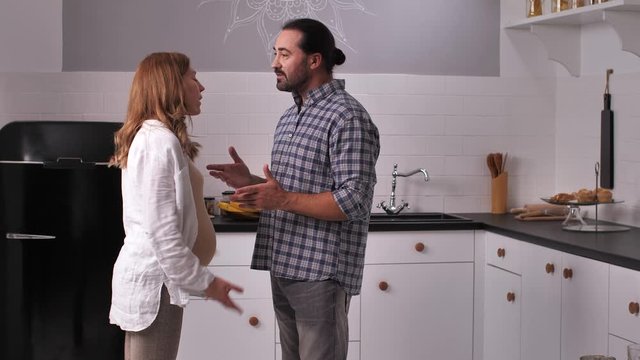 Close-up of future parents arguing in modern cozy kitchen. Problems in relationships during pregnancy, need for support, patience and understanding during mood swings of pregnant women