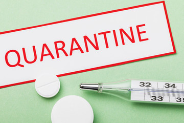 Obraz premium Tag with text, thermometer and pills on a green background. Quarantine concept
