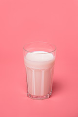 a glass of milk on a pink background