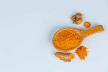 Turmeric root and turmeric  powder  in a wooden spoon isolated on white background.
