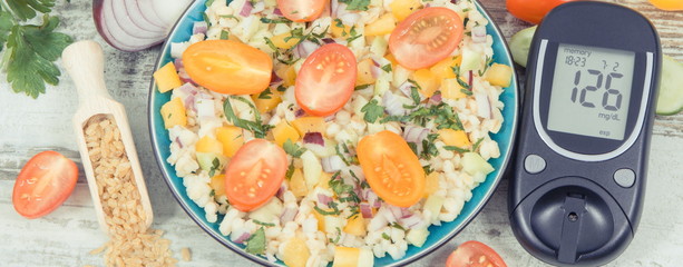 Glucose meter with sugar level, salad with vegetables and bulgur groats, tape measure. Diabetes and...