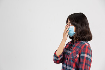 Cute girl is wearing mask and putting her hand up while close mouth by hand on white background.