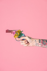 Tattooed hand holding a rainbow gun