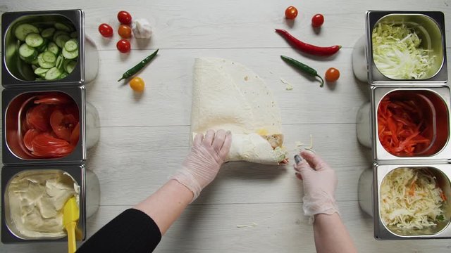 Top view of chef hands in white gloves wraps doner kebab shawarma in pita or lavash. Shawarma with chicken cutlet, pappers, cheese and vegetable