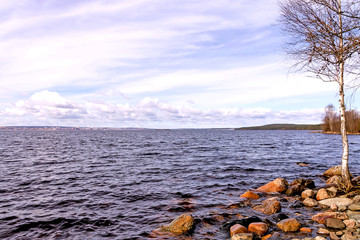 The body of water of Lake Onega against the backdrop of blue sky and rocky shore.