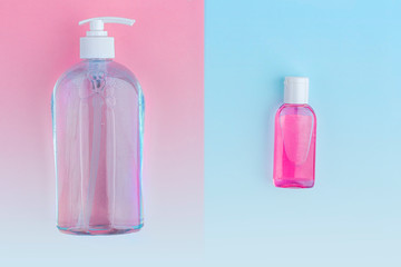 A big and little bottles with antiseptic sanitizer gel for washing hands on blue and pink background. Alcohol gel as coronavirus prevention. Viral disease prevention concept. Copy space for text