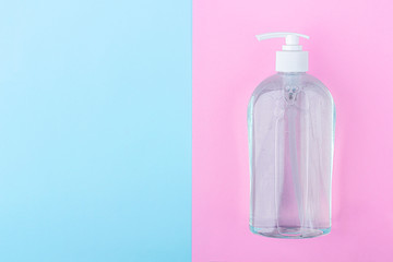 A big bottle with antiseptic sanitizer gel for washing hands on blue and pink background. Alcohol gel as coronavirus prevention. Viral disease prevention concept. Copy space for text, flat lay