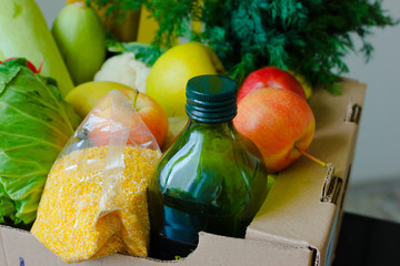 Box with fruits and vegetables apples cabbage radish zucchini oil, grits close up. Food delivery services during coronavirus pandemic and social distancing. Shopping online. Meals Food Donations.