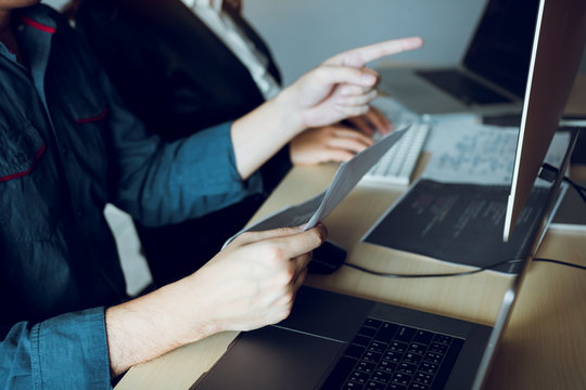 Two software developers are using computers to work together with their partner at the office desk.