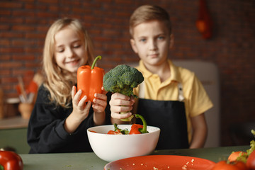 Brother and sister. Children prepare the salad. Kids in the kitchen.