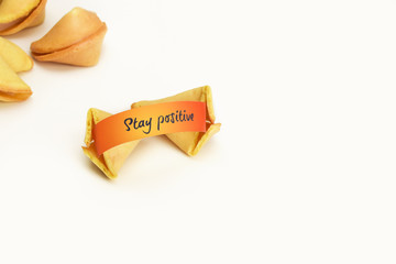 Stay positive on orange wishes paper in Chinese fortune cookie on white background. Copy space.