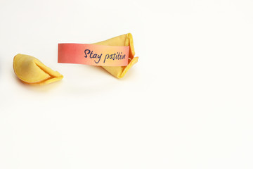 Stay positive wish on orange paper in a fortune cookie on white background.