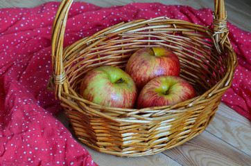 Rustic still life apples in a straw basket on a wooden table top view
