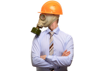 The protected businessman in a gas mask, construction helmet, shirt and tie crossed his arms on his chest, looks to the side. Isolated