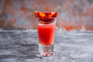 Strong red cocktail in shots on the rustic background. Selective focus. Shallow depth of field.
