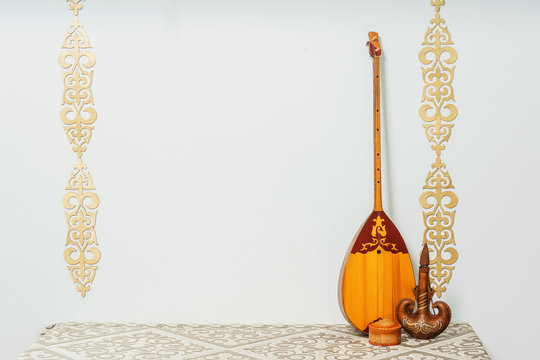 Kazakh national musical instrument dombra on a white background. National Kazakh decor gold ornaments and household items. Kazakh Kyrgyz ethnic background