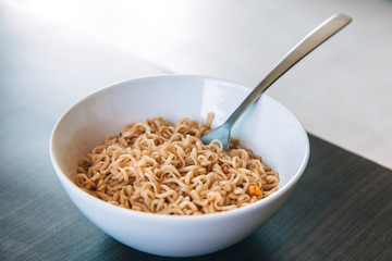 Instant noodles in a white plate for lunch, the concept of cheap food or food delivery, selective focus, close-up