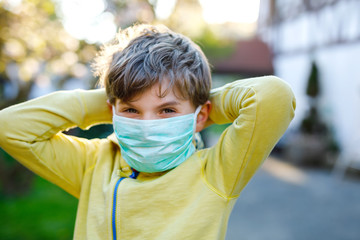 Adorable kid boy in medical mask as protection against pandemic coronavirus quarantine disease....