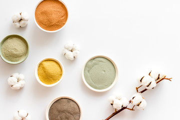 Yellow, red, white, blue and black cosmetic clay on white table top view copy space